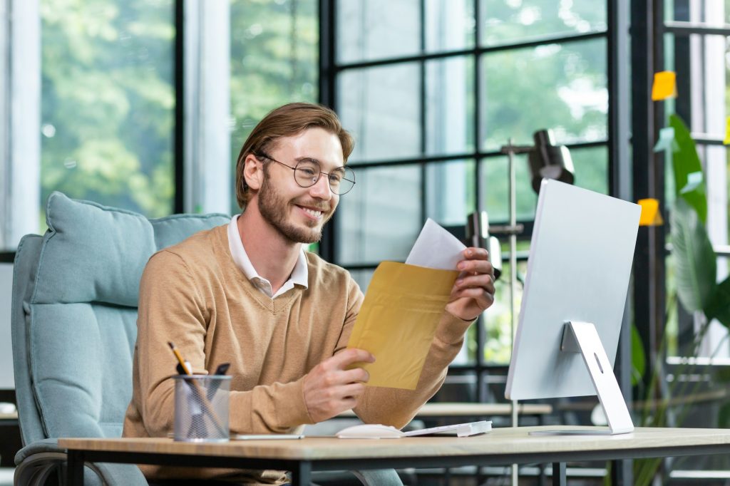 Jeune homme d'affaires prospère dans un intérieur décontracté de bureau, homme blond lisant une lettre postale avec