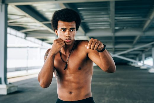 Kickboxer torse nu debout sous un pont en position de combat