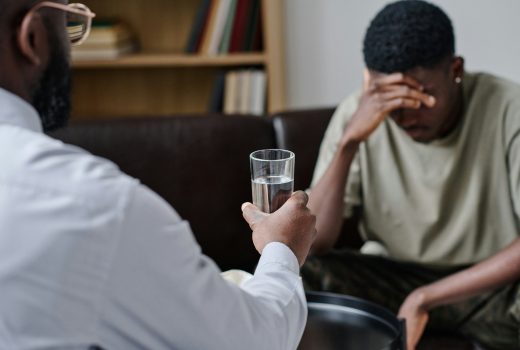 Psychothérapeute africain donnant un verre d'eau pour soutenir le patient au bureau pendant une séance de psychothérapie