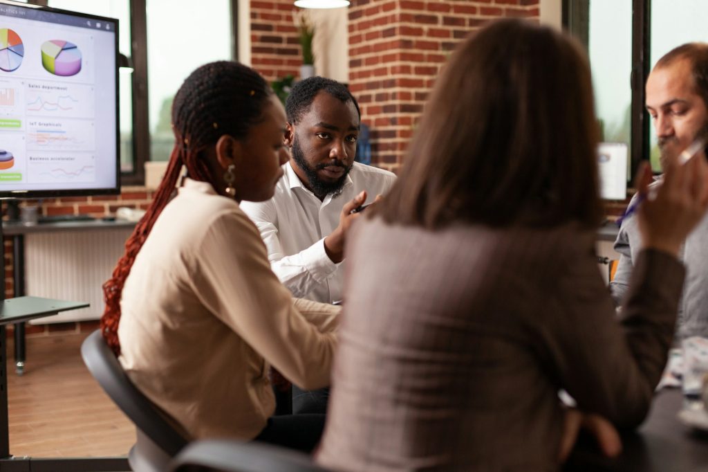Homme afro-américain expliquant la présentation de l'entreprise de planification de la stratégie de gestion lors d'une réunion d'affaires dans un bureau de démarrage.
