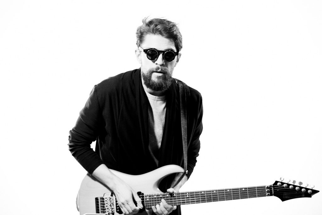 Homme avec guitare musique performance divertissement artiste contemporain lunettes de soleil studio.