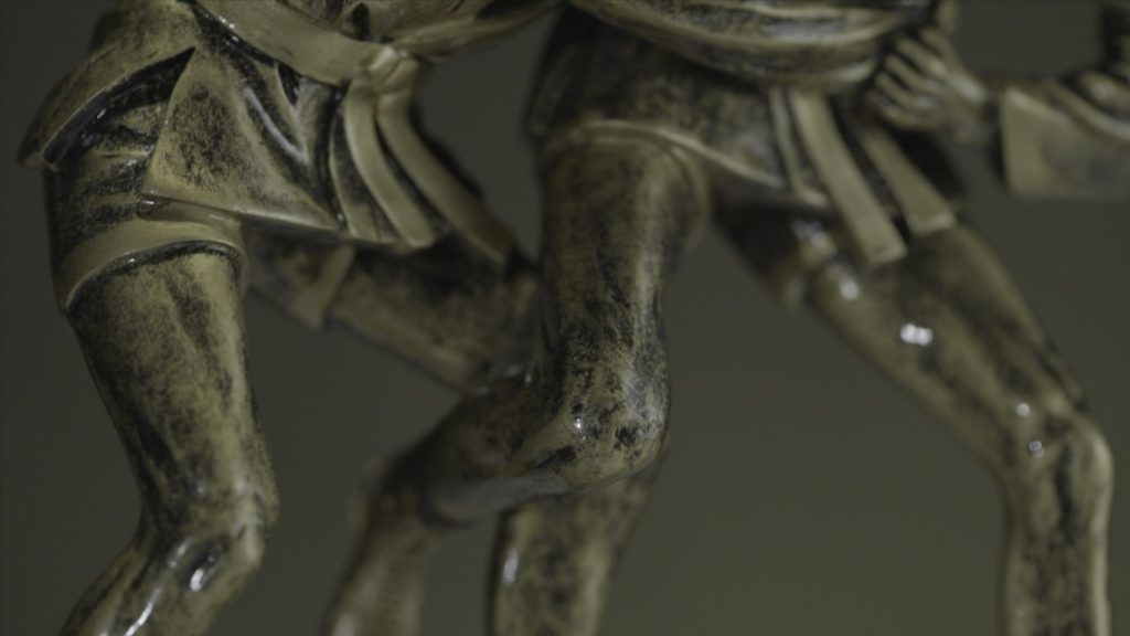 Statuette en bronze représentant deux hommes luttant l'un contre l'autre en gros plan.
