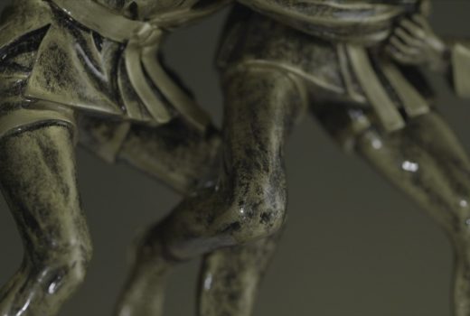 Statuette en bronze représentant deux hommes luttant l'un contre l'autre en gros plan.