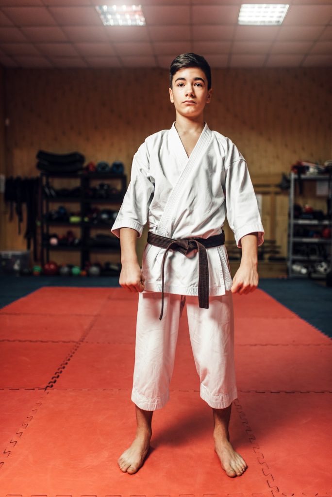 Arts martiaux, jeune combattant en kimono blanc et ceinture noire en séance d'entraînement en salle de sport