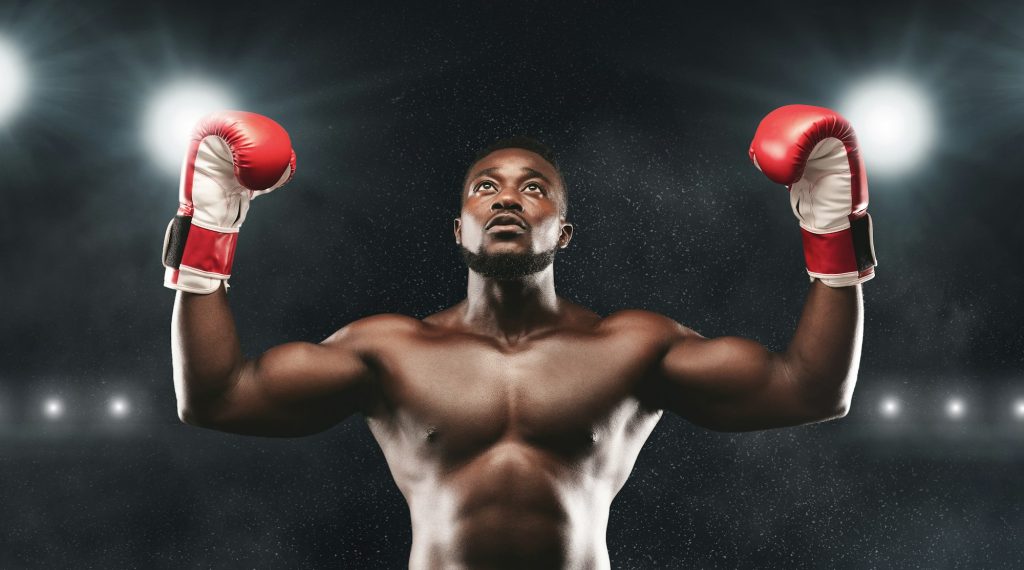 Joyeux combattant africain célébrant la victoire avec les mains en l'air, arène de boxe, panorama