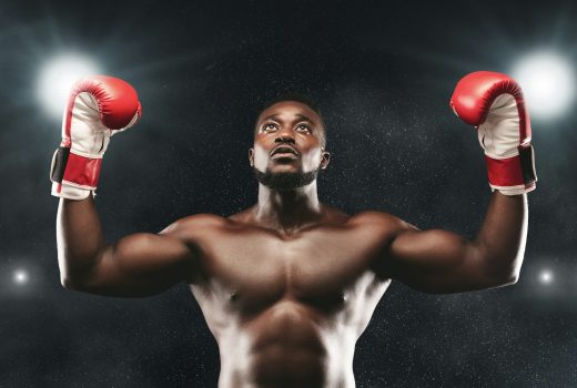 Joyeux combattant africain célébrant la victoire avec les mains en l'air, arène de boxe, panorama
