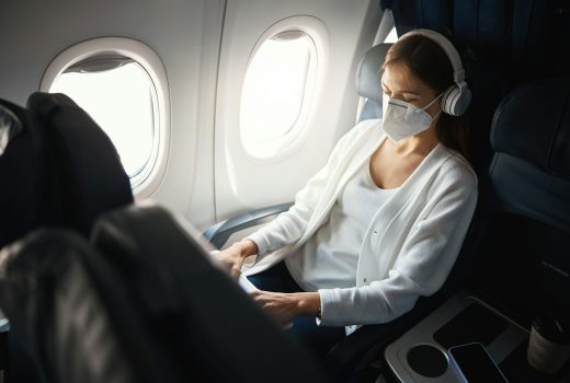 Jeune femme portant un respirateur alors qu'elle était assise dans un avion et écoutait de la musique avec des écouteurs