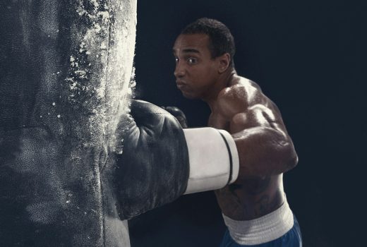 Main de boxeur et sac de boxe sur fond noir.