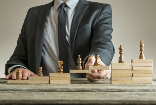 Image conceptuelle de la gestion de carrière avec un homme d'affaires formant un pont de blocs de construction en bois pour les pièces d'échecs se développant du pion au roi.