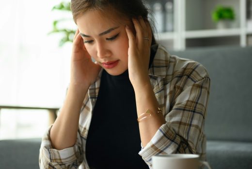 Jeune femme stressée tenant la tête dans les mains, gérant les finances du ménage frustrée par les problèmes financiers familiaux.