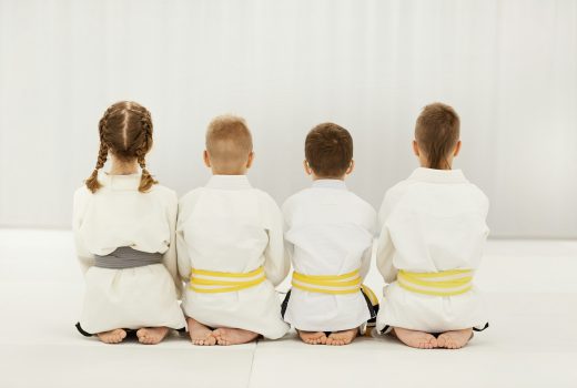 Vue arrière d'enfants pieds nus en kimono blanc assis sur le sol ensemble dans une rangée