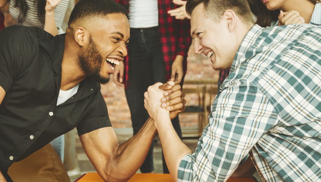 Des amis joyeux s'amusent à faire un bras de fer lors d'une fête entre amis.