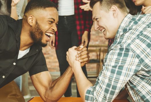 Des amis joyeux s'amusent à faire un bras de fer lors d'une fête entre amis.