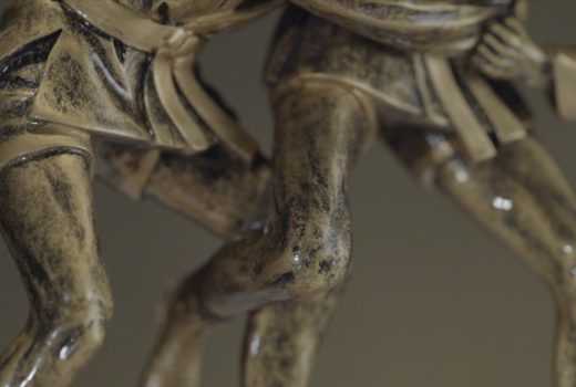 La statuette en bronze de deux hommes se frappant les uns avec les autres.