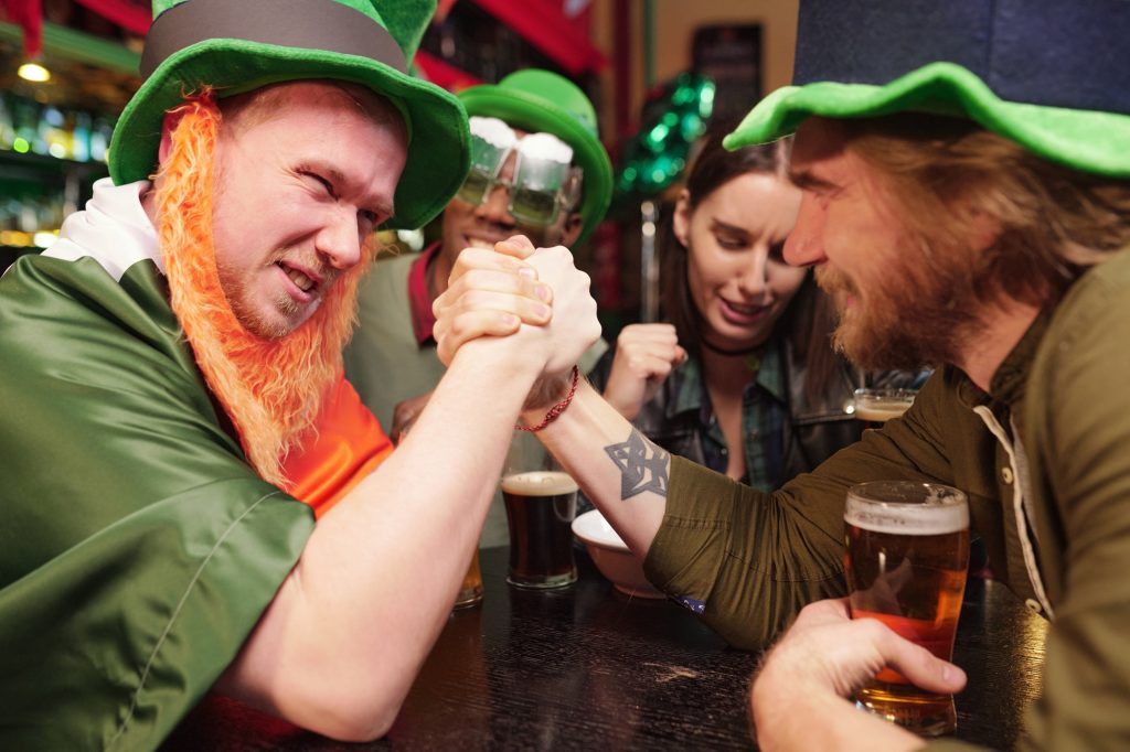 Un jeune homme se tient la main et rivalise les uns avec les autres lors d'un match de lutte de bras à une table dans un bar