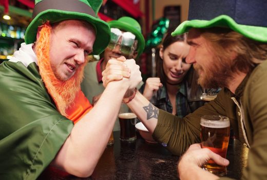 Un jeune homme se tient la main et rivalise les uns avec les autres lors d'un match de lutte de bras à une table dans un bar