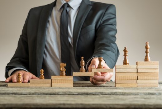 Image conceptuelle de la gestion de carrière avec un homme d'affaires formant un pont de blocs de construction en bois pour les pièces d'échecs se développant du pion au roi.