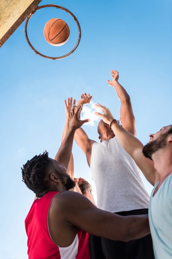 Vue à angle bas des basketteurs multiculturels qui luttent pour attraper le ballon